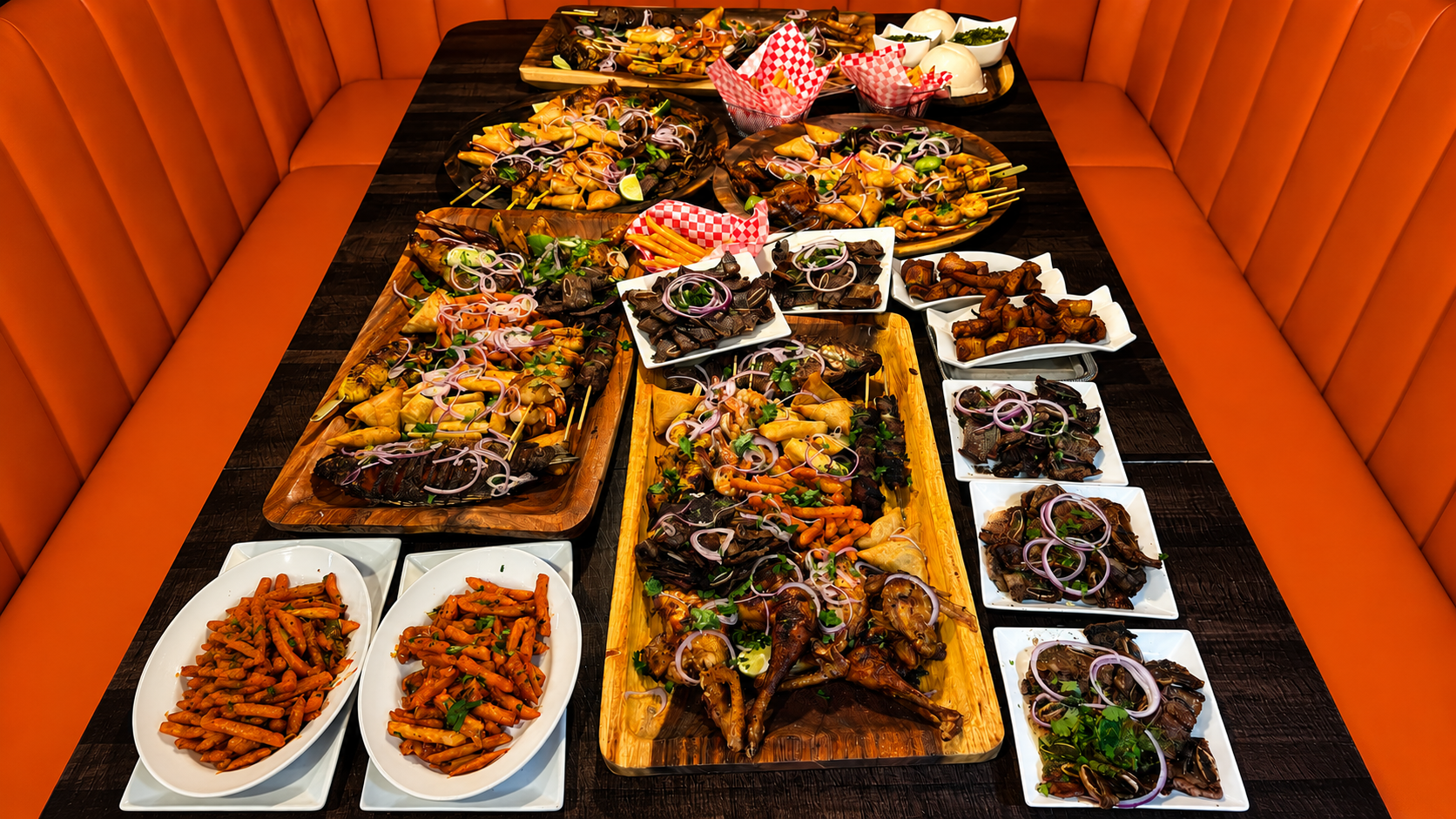 A long Kilimanjaro VIP table laid with grilled meats, samosas, skewers and sides for sharing