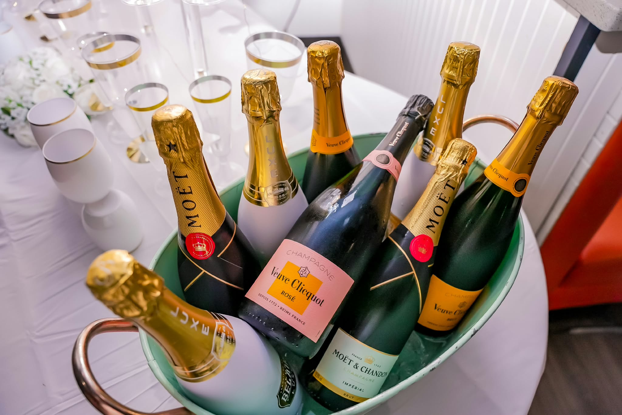 Champagne bottles chilling in an ice bucket beside gold-rimmed flutes